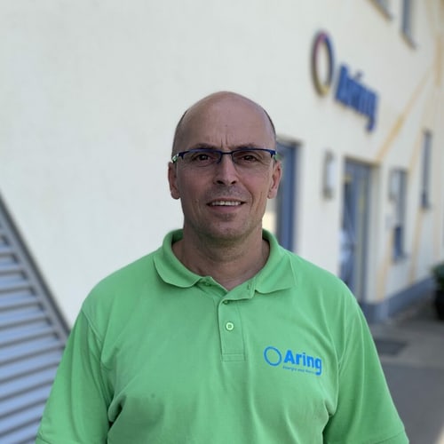 Mitarbeiter im grünen Aring-Poloshirt vor dem Firmengebäude von Aring.
